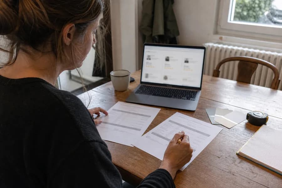 Une particulière compare plusieurs propositions posées sur sa table.